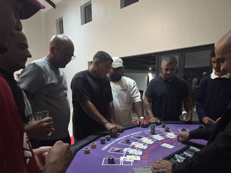 Guests standing around a blackjack table as the dealer plays a hand