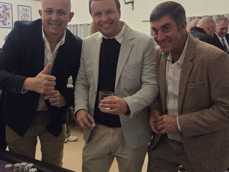 Three smiling guests beside a roulette table at a fun casino night